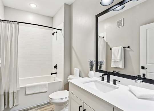 A white bathroom with a toilet, sink, and shower.