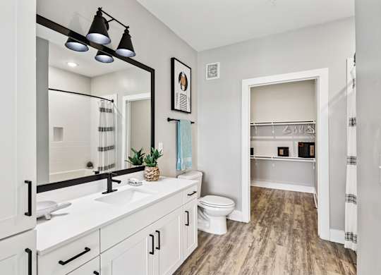 A bathroom with a white vanity and a toilet in the background.
