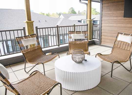 Cozy balcony with wicker style chairs and large flatscreen television at Novel Cary