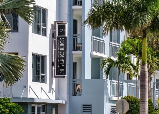 South of Atlantic Apartment Entrance Framed by Palm Trees and Custom Sign