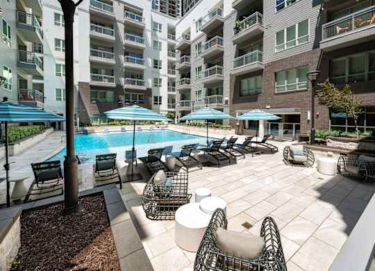 A large outdoor patio with a pool and chairs.