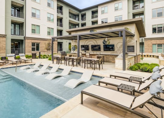 Poolside Dining Tables and Chaise Lounges Beside In-Water Loungers