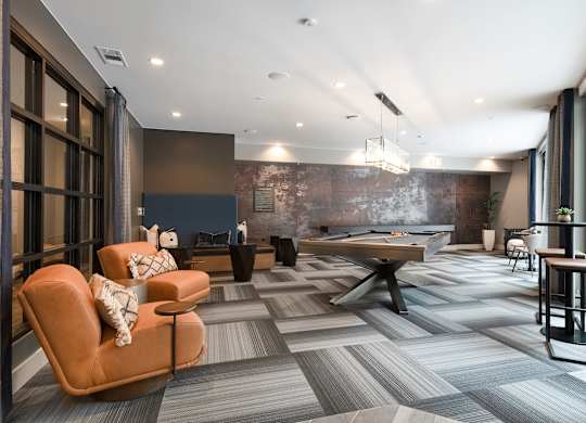 Modern Game Lounge with Pool Table, Casual Seating, and Industrial Accents
