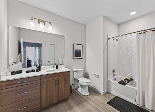 Apartment bathroom with a double vanity, toilet, soaking tub, and subway tile surround.