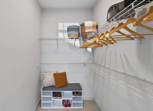 Large closet with wraparound wire shelving, hanging rods, and a storage bench.