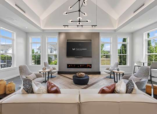 Clubhouse lounge with a modern fireplace, sectional sofa, armchairs, and large windows.