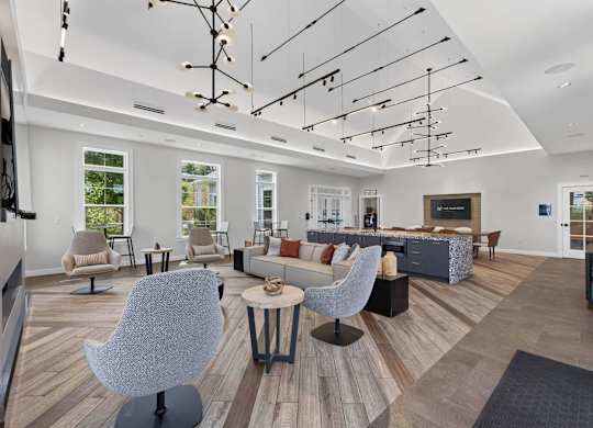 Spacious clubhouse lounge with multiple seating areas, high ceilings, and modern lighting.
