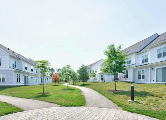 Curving paved path between residential buildings and landscaped lawn areas.