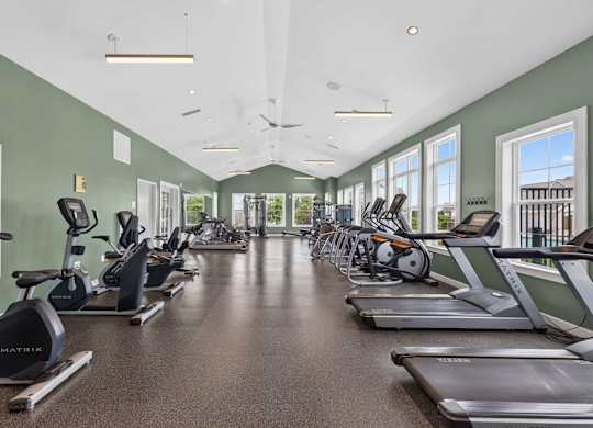 Fitness studio with cardio machines and large windows at The Madison at Marshfield.
