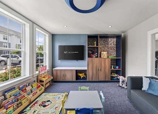Indoor playroom with books, toys, child-size tables, and soft seating at The Madison at Marshfield.