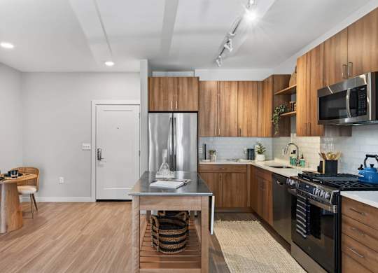 Apartment kitchen with wood cabinetry, stainless steel appliances, and island at The Madison at Marshfield.