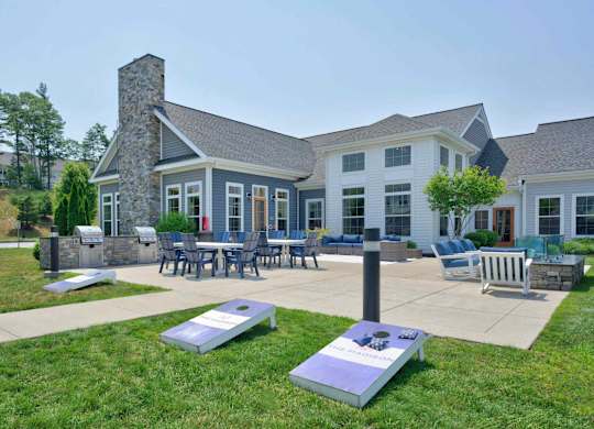 Clubhouse patio with dining tables, lawn seating, and cornhole at The Madison at Marshfield.