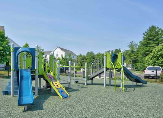 Colorful outdoor playground with two slides, climbing structures, and open play space.