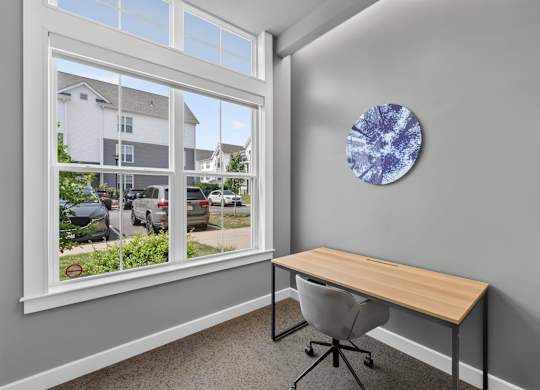 Reservable workspace with a desk, chair, window, and abstract wall art.