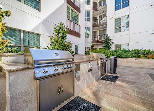 Outdoor barbecue stations with stainless steel grills, set within beautifully landscaped courtyards
