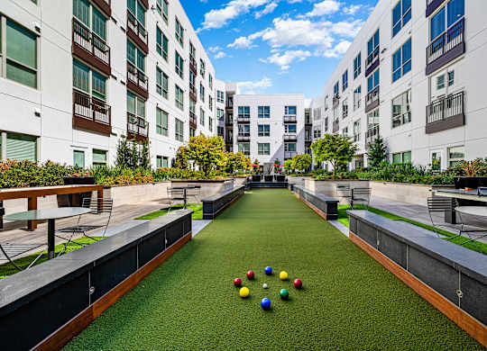 Bocce ball court surrounded by lush greenery and modern architecture, creating a vibrant community setting