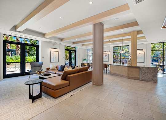 Stylish clubroom lounge with designer seating, wood accents, and walls of windows for gathering and relaxing