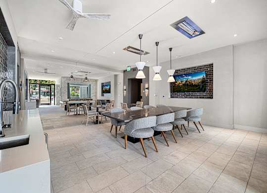 Clubroom with a long dining table, plush seating, and entertainment screens designed for community gatherings