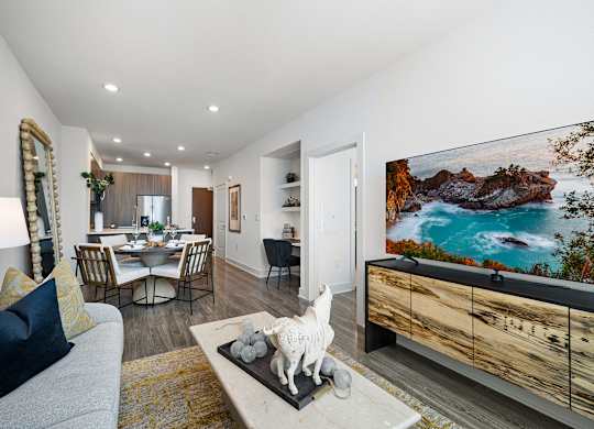 Bright living room with contemporary furnishings, wall-mounted TV, and open dining layout
