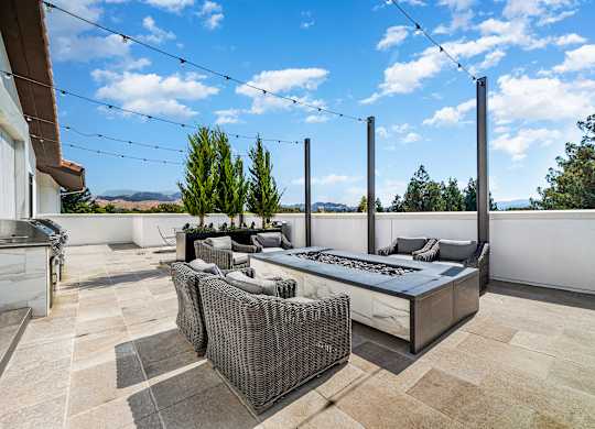 Rooftop terrace with lounge seating, outdoor firepit, and views of rolling hills