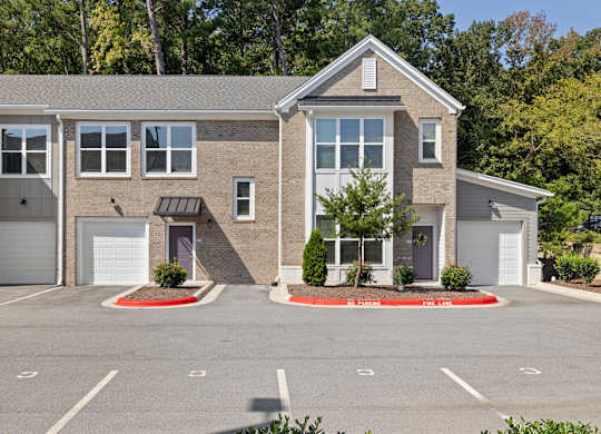 A two-story building with a garage door and a driveway in front.