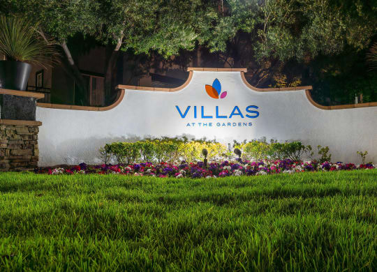 Villas at the Gardens Illuminated Entry Sign with Lush Lawn and Colorful Flowers
