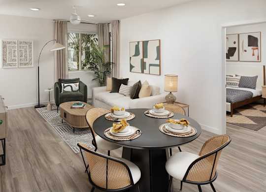 Round dining table with cane chairs in front of the living area, with a bedroom visible through a doorway to one side.