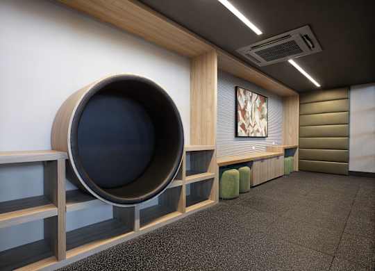 Children's lounge with a large circular padded nook set into a timber wall, cushioned stools and a bench running opposite.