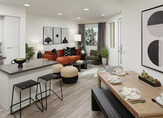 Open plan with a rust sofa, a grey quartz island with two black stools and a long timber dining table set beside it.