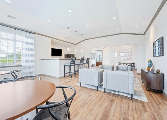 a resident clubhouse with couches tables and chairs and a kitchenette