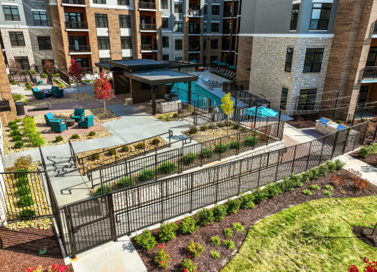 an aerial view of a courtyard with a fence and plants in front of a building