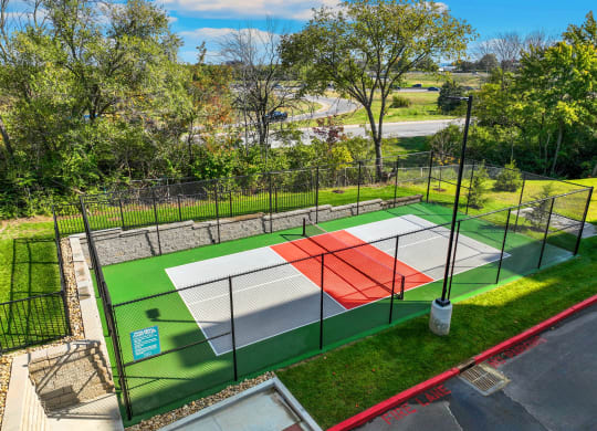 a tennis court with a fence around it in a park
