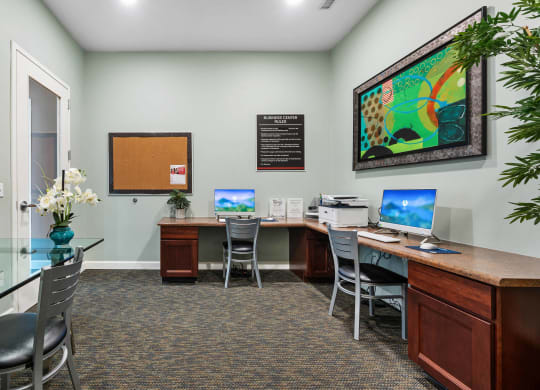 a office with two computers and a desk with chairs