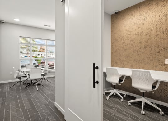 a conference room with white desks and chairs and a window
