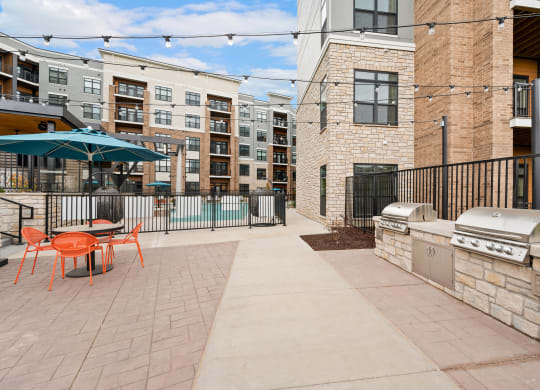 our patio has a grill and a table with chairs and an umbrella