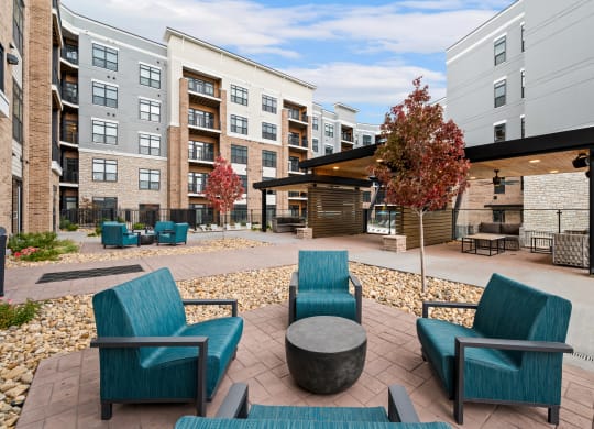 an outdoor lounge area with chairs and tables at an apartment complex