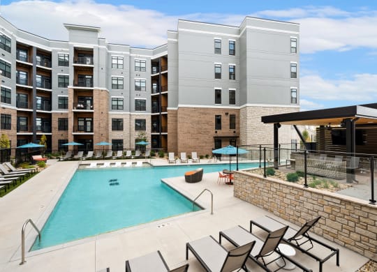 a swimming pool with chairs and an apartment building