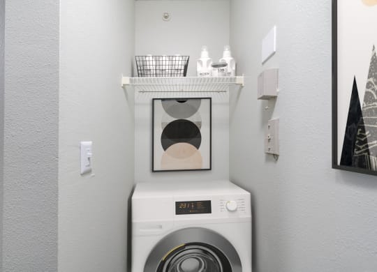 a white washer and dryer in a laundry room with a shelf above it