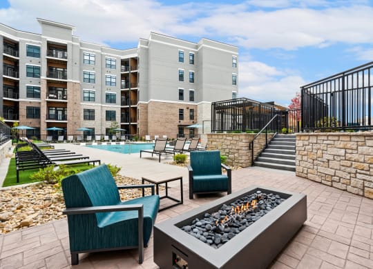 an outdoor patio with chairs and a fire pit and an apartment building