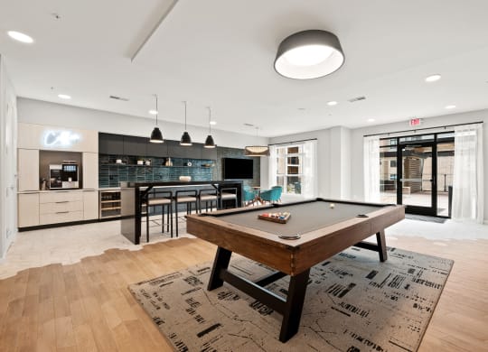 a living room with a pool table and a kitchen with a bar