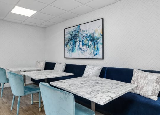 a seating area with blue chairs and white tables with marble tops
