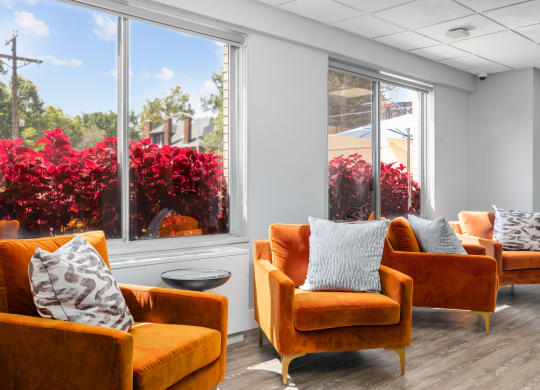 a seating area with orange chairs and red flowers in the background