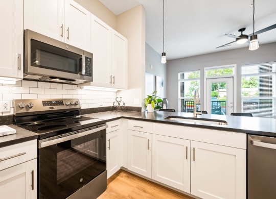 a kitchen with white cabinets and black counter tops and a stove and microwave