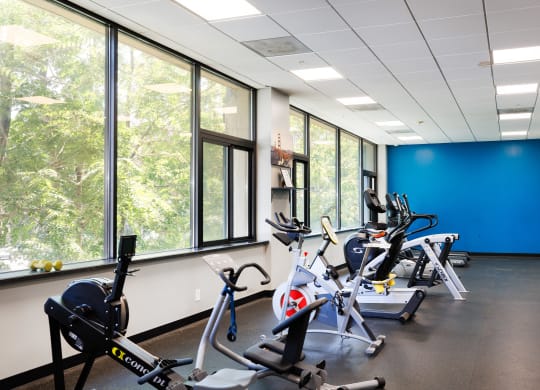 a fitness room with exercise bikes and windows