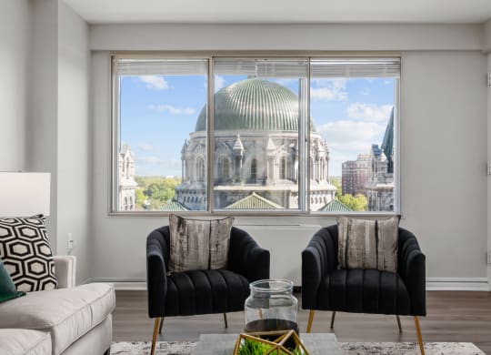 a living room with two black chairs and a large window with a view of the dome of