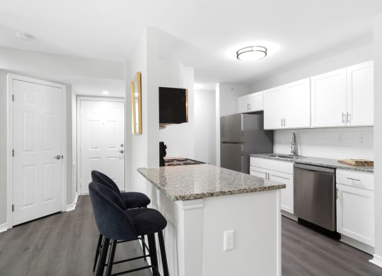 a kitchen with an island and a counter top with black chairs