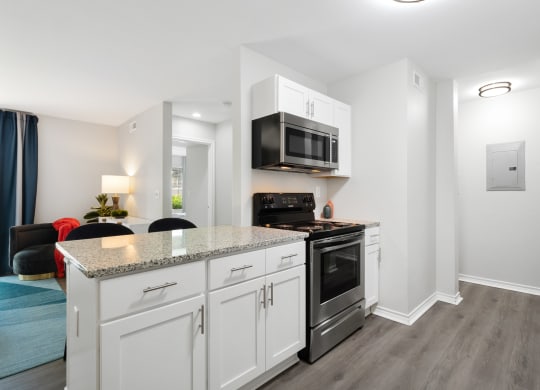 a kitchen with white cabinetry and a counter top with a stove and a microwave