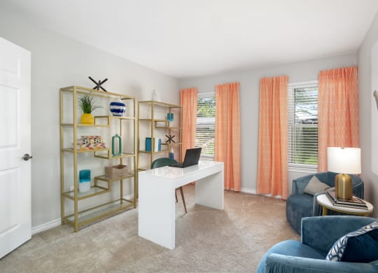 a living room with a desk with a laptop and a couch
