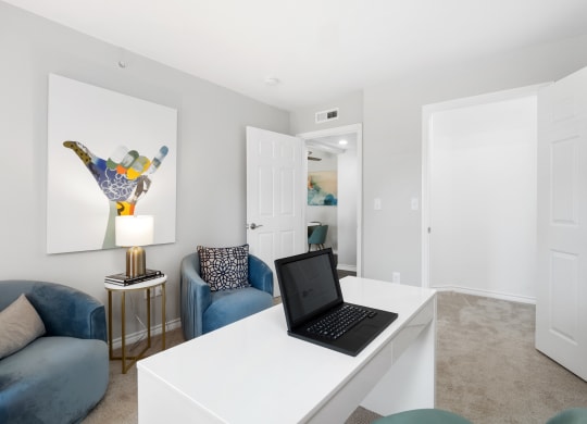 a living room with a desk with a laptop on it