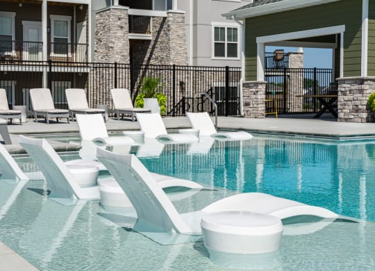 a swimming pool with white lounge chairs and a house in the background